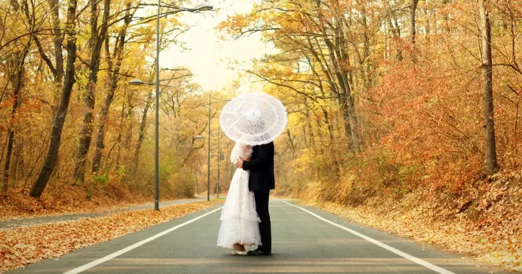 bride and groom sneaking a kiss during thier fall wedding