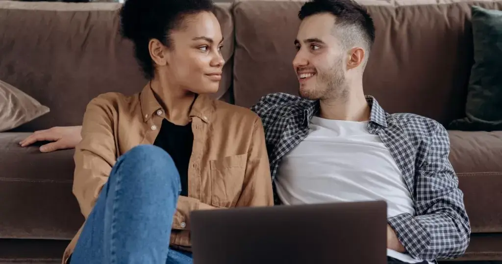 Couple sitting on the floor listening to music on a laptop