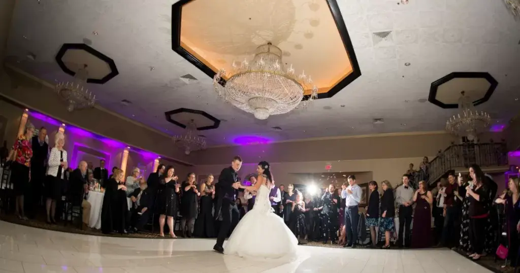 Couple having their first dance surrounded by their family and friends.