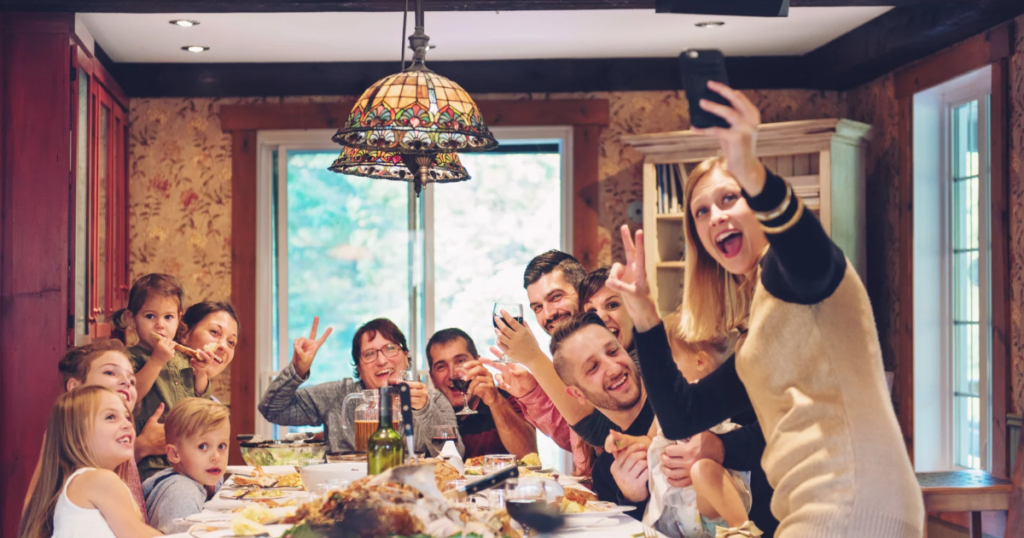 Family gathered around a holiday dinner table, smiling and taking a selfie together, capturing joyful moments during the festive season.